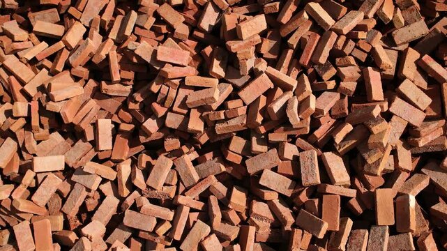 Large Stack of Red Bricks at Construction Material Warehouse. Wide static shot of a massive stack of red bricks filling the entire frame at a construction materials storage area. Slight handheld camer