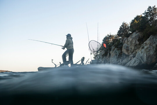 Man standing on a kayak while fishing on lake