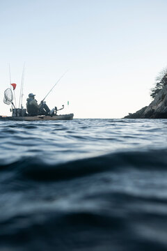 Person in a fishing kayak on calm ocean water