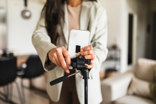Woman adjusting smart phone on tripod at home
