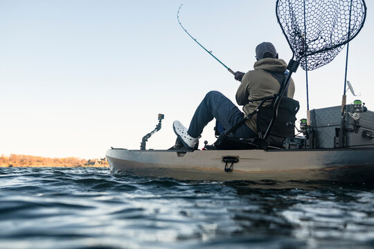 Man reeling in a fish from his fishing kayak