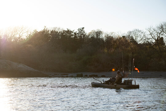 Man on a fishing kayak at sunset