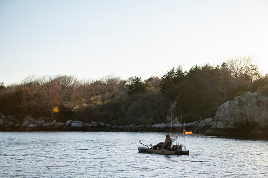 Person kayak fishing during a calm quiet sunset
