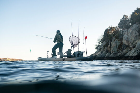 Man standing on a fishing kayak casting line