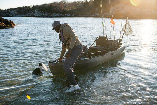 Man launching his fully rigged fishing kayak