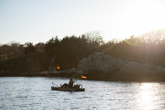 Man kayak fishing along a rocky coastline