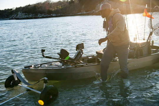 Man launching his fishing kayak at sunset