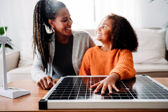 Happy mother and daughter with solar panel at home