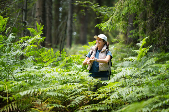 Hiker using smartwatch in lush green forest during summer adventure