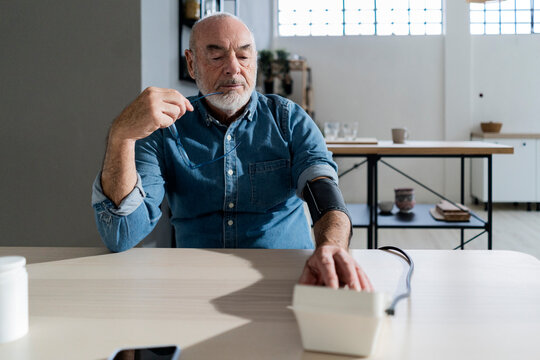 Man checking blood pressure at dining table in living room