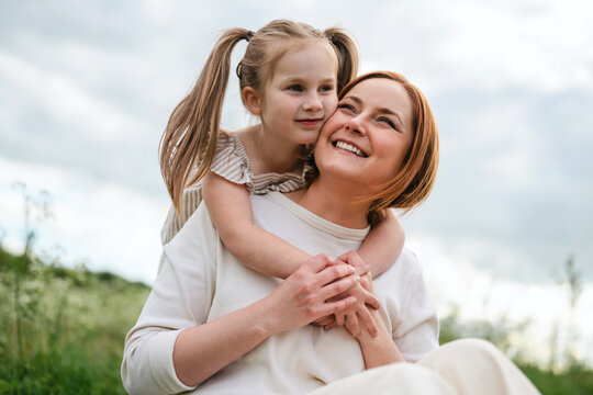 Smiling mother and daughter hugging outdoors