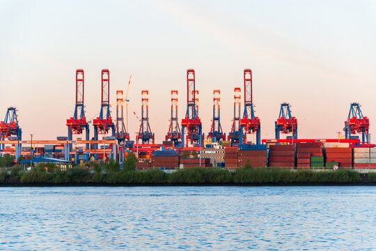 Industrial Hamburg harbor with container crane at sunset