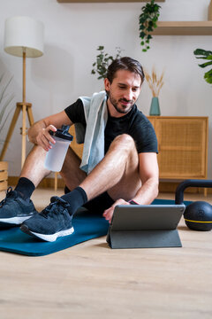 Motivated person using training app and hydrating after home workout
