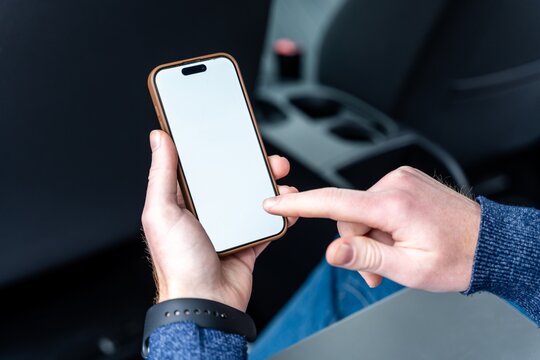 Hands tapping a blank screen smartphone in a car
