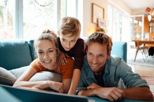 Happy parents with son watching video on laptop at home
