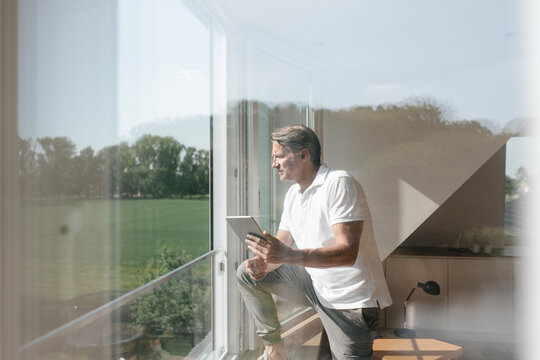 Mature man using tablet at the window