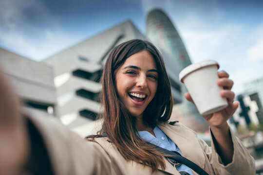 Happy young woman taking selfie with coffee cup