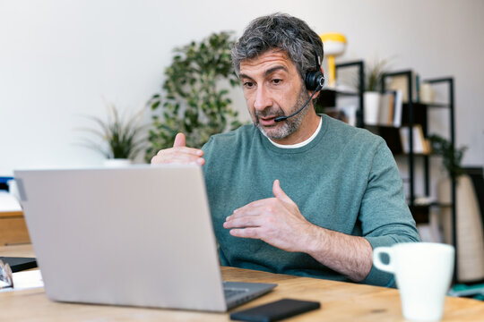 Consultant gesturing during a virtual meeting on a laptop indoors