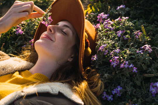 Woman lying in meadow enjoying fragrance of a flower