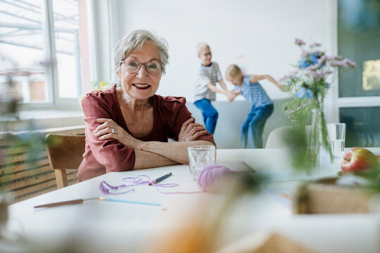 Grandmother looking at camera while grandchild plays at home