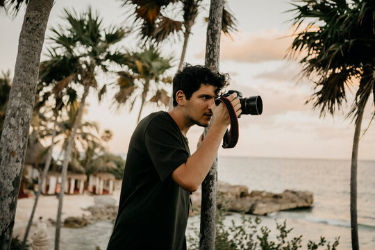 Mexico, Quintana Roo, Tulum, young man taking pictures on the beach