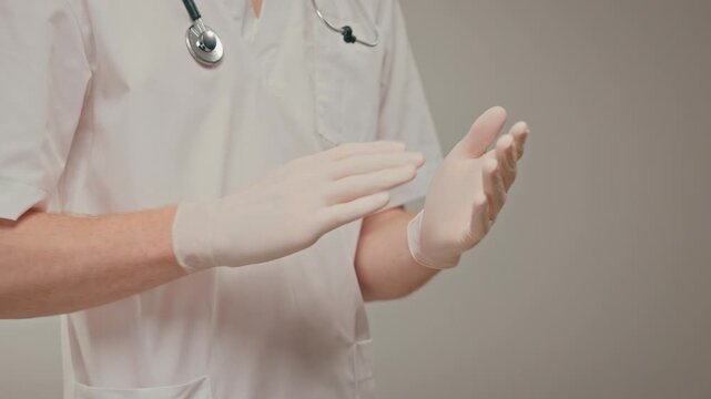 Caucasian physician pulling on surgical glove closeup, stethoscope visible, rapid but careful donning before emergency procedure,