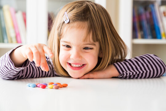 Smiling little girl playing with chocolate buttons