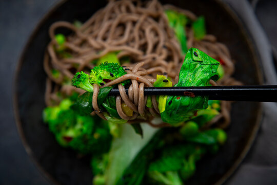 Chopstick lifting soba noodle with broccoli and pak choi