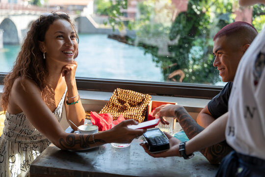 Portrait of smiling woman paying with smartphone at coffee shop