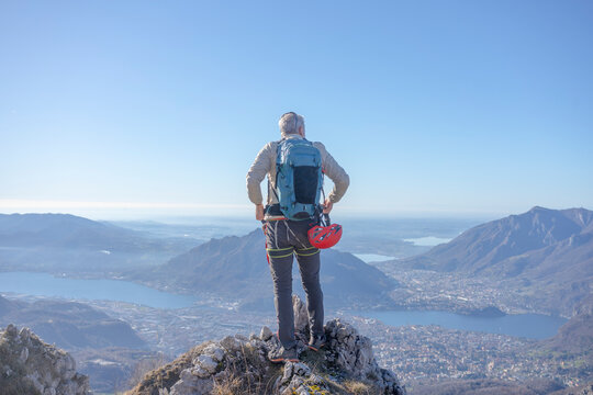 Rear view of climber on mountain peak looking at Lecco Italy