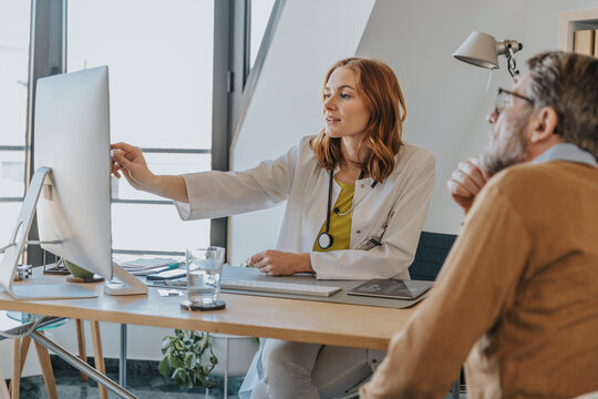 Female doctor explaining over computer while sitting with patient at doctor's office