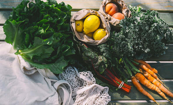 Fresh organic leafy vegetables and fruits on wooden table