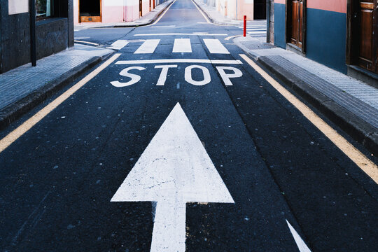 Empty urban road with stop sign and painted arrow