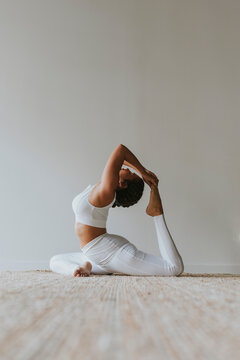 Flexible yogi practicing yoga by wall at studio