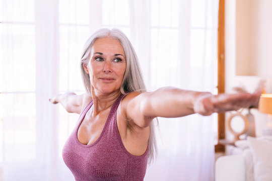 Smiling woman with arms outstretched exercising at home