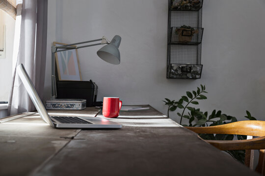 Desk with laptop and coffee cup at home office
