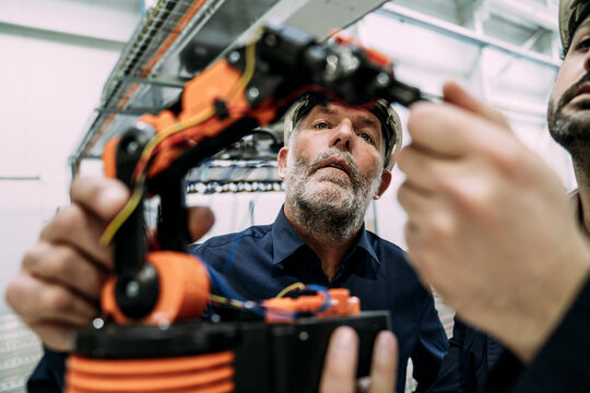 Engineers working on a robotic arm in a factory setting