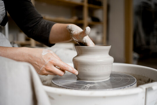 Young craftswoman making flower pot on pottery wheel