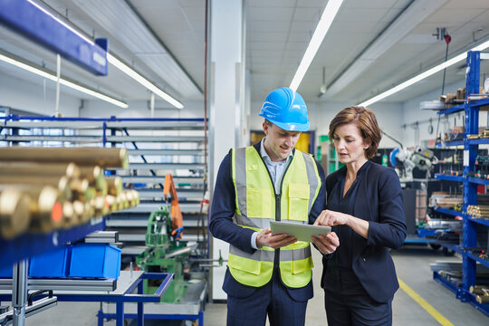 Female manager discussing over digital tablet with male supervisor in industry