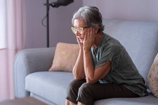 Lonely woman with hands on chin sitting in living room