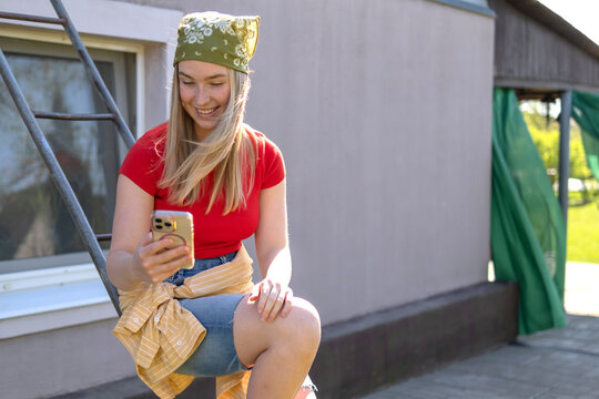 Smiling woman with bandana taking selfie in sunny spring garden