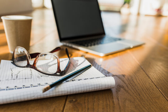 Laptop, notepad and glasses on wooden floor