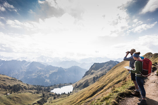 Germany, Bavaria, Oberstdorf, two hikers with map and binoculars in alpine scenery