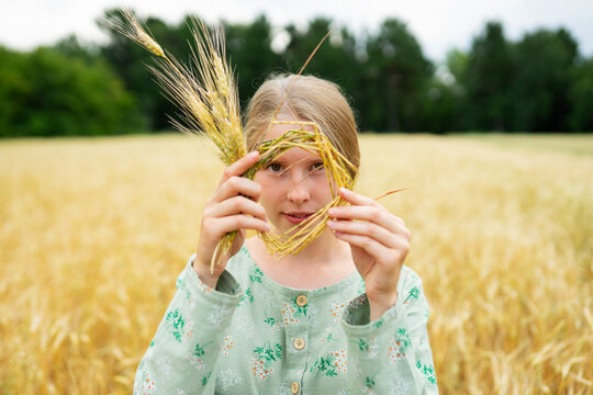 Woman holding a wheat wreath over face in a summer field