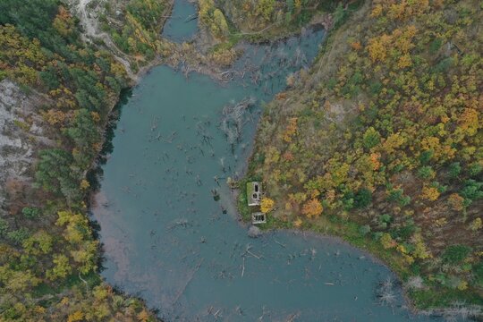 Aerial view of Lago di Poggio Baldi surrounded by dense autumn forests and submerged tree trunks in Santa Sofia, Emilia-Romagna, Italy.