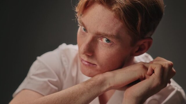 Intense studio closeup of white male actor leaning on hands with piercing stare, dramatic shadows and spotlight highlights, skin