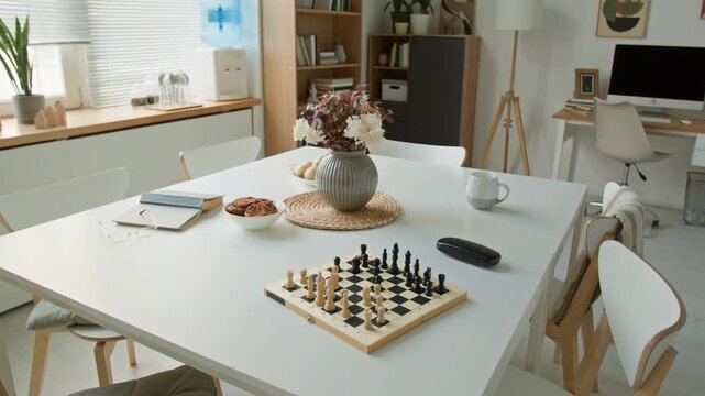 Chessboard, flower vase, and snacks resting on table in empty retirement home common room. Video for promoting senior care, assisted living, and elderly recreation programs