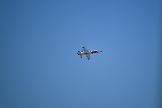 Red and white jet aircraft in clear blue sky