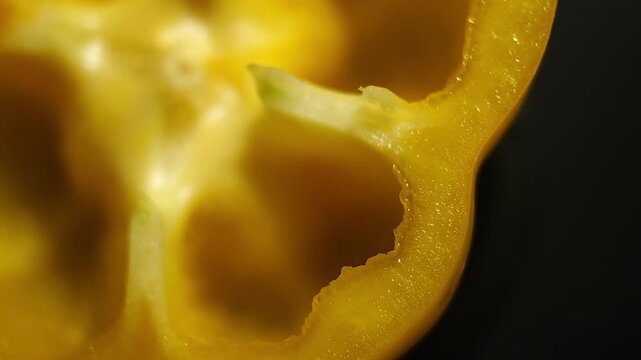 50p macro lens top view shot of a yellow pepper slice rotating to reveal texture, seeds and vibrant natural color