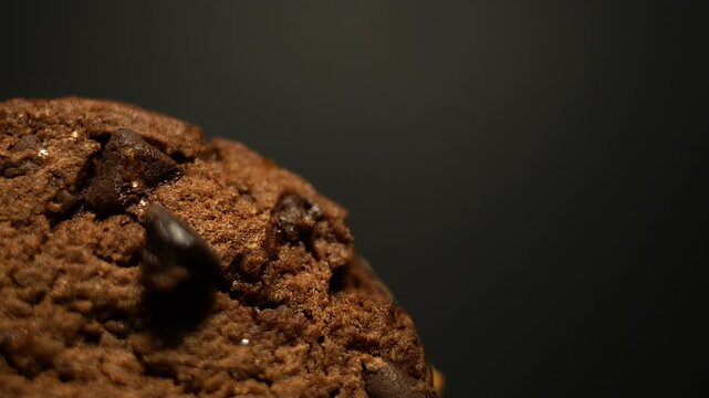 50p macro close up side view shot of a brown cookie rotating to reveal texture, crumbs and baked surface details